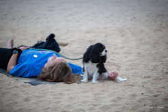 Une pratiquante allongée sur son tapis en extérieur, avec un chien à ses côtés.